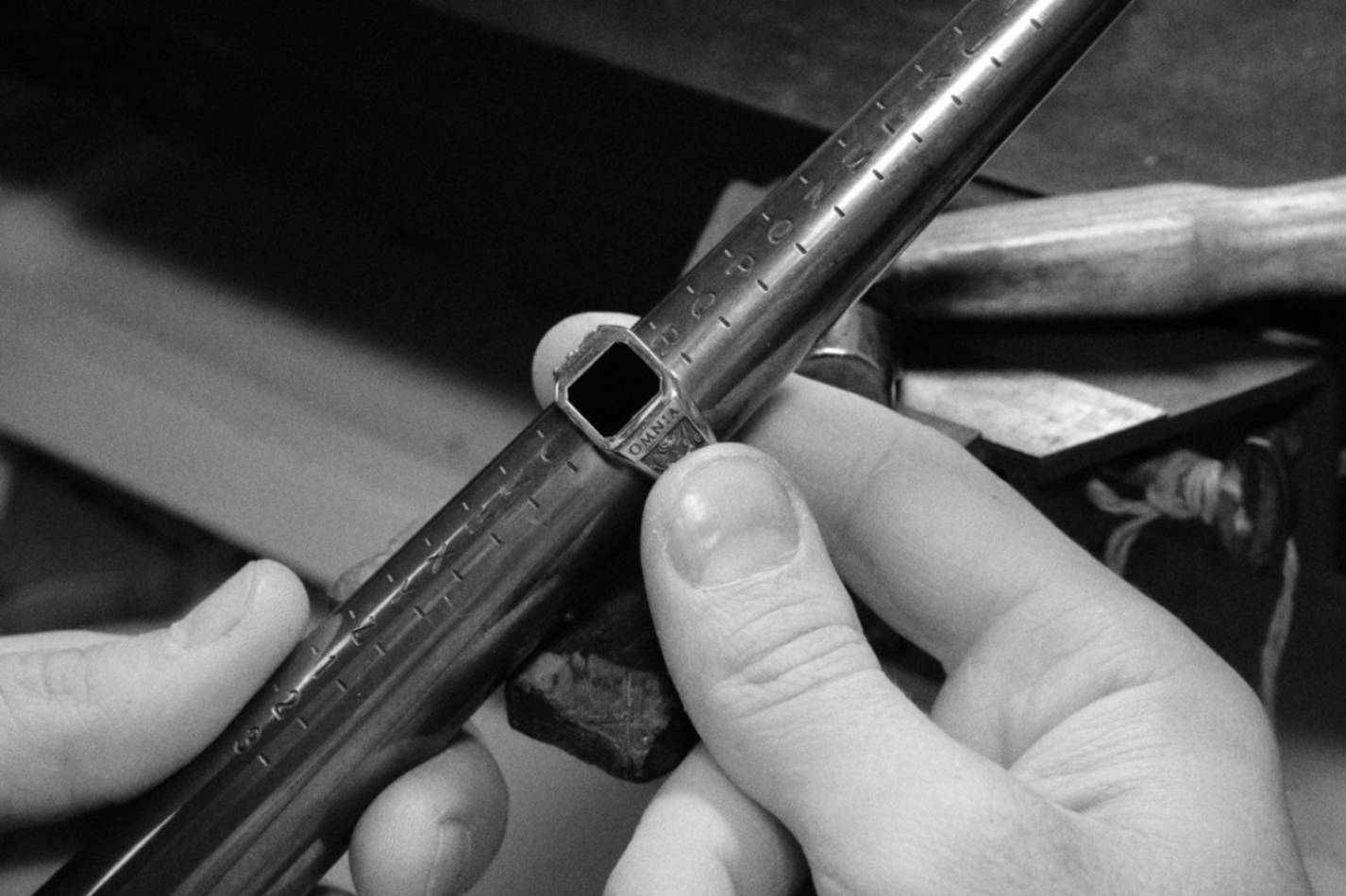 close up hands holding a vanitas silver ring made by sar in a sizing tool